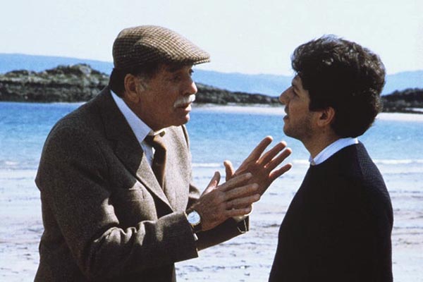 Dos hombres hablando en la playa, escena de la película Un tipo genial ambientada en Escocia